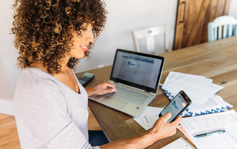 Woman checking phone and computer